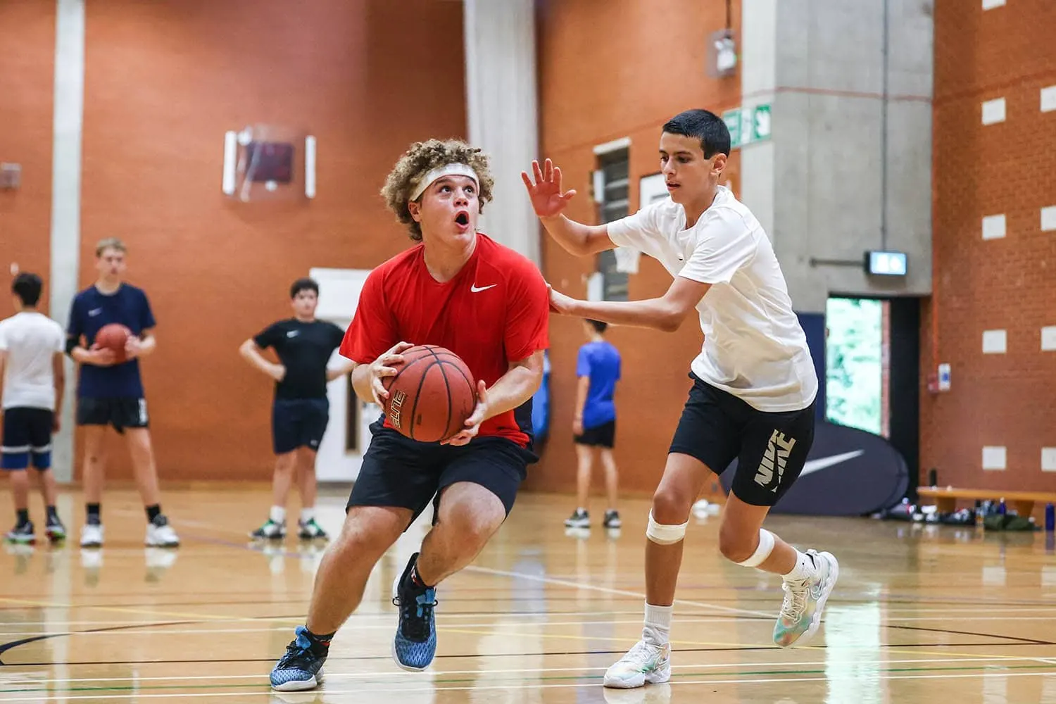Due ragazzi giocano a basket in una palestra durante un camp